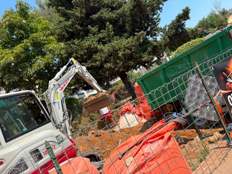 Pelle mécanique démolissant une structure derrière un filet de chantier