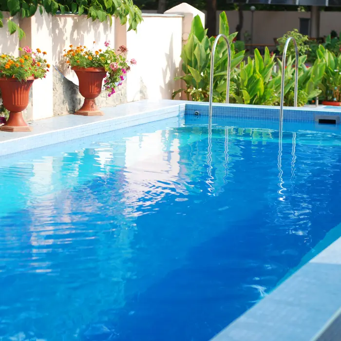Piscine bleue avec margelles et massifs fleuris